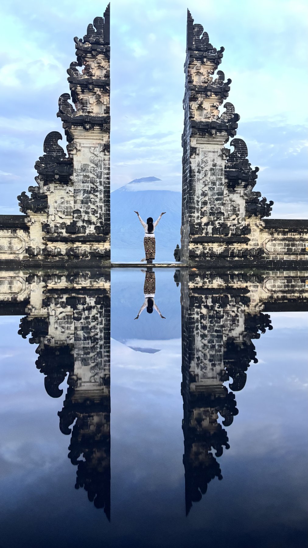 Gates of Heaven temple, Bali — arms raised in the mirror reflection pool